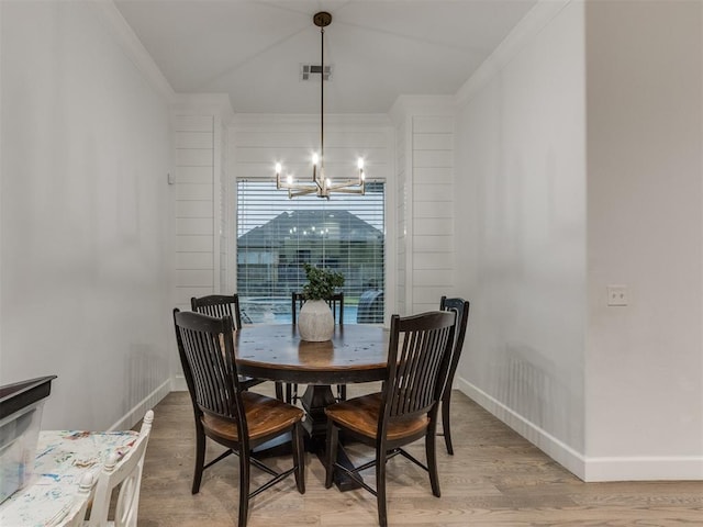 dining area featuring wood-type flooring, crown molding, and a chandelier