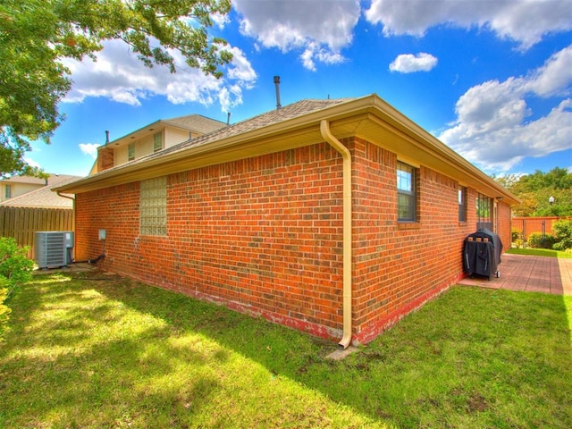 view of home's exterior with a lawn, central AC unit, and a patio area