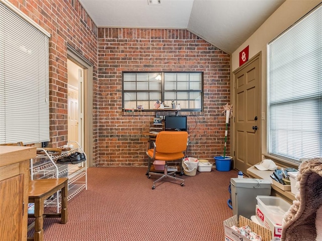 office space featuring carpet, lofted ceiling, and brick wall