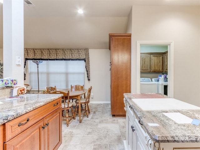 kitchen with white cabinets, separate washer and dryer, and light stone countertops