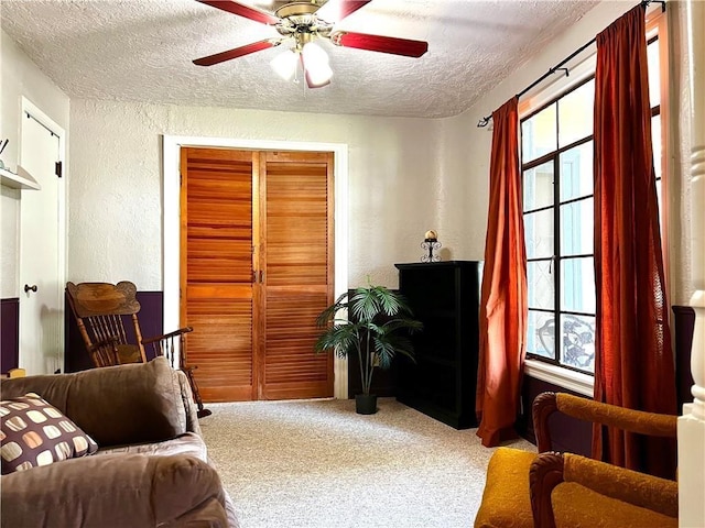 living room featuring ceiling fan, carpet flooring, and a textured ceiling