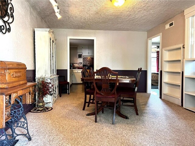 carpeted dining room featuring a textured ceiling