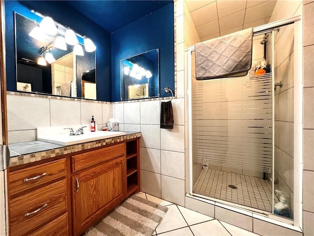 bathroom with tile patterned flooring, vanity, tile walls, and an enclosed shower