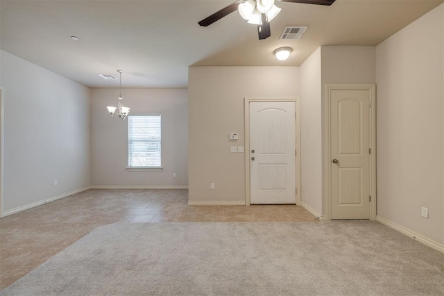 carpeted spare room featuring ceiling fan with notable chandelier