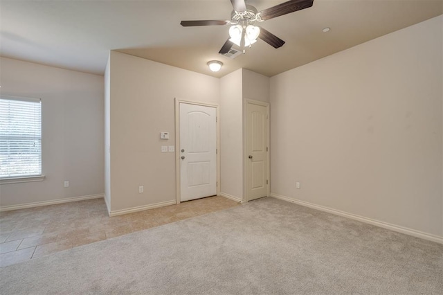 empty room featuring ceiling fan and light colored carpet