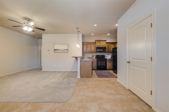 kitchen featuring ceiling fan, a kitchen breakfast bar, pendant lighting, light carpet, and black appliances