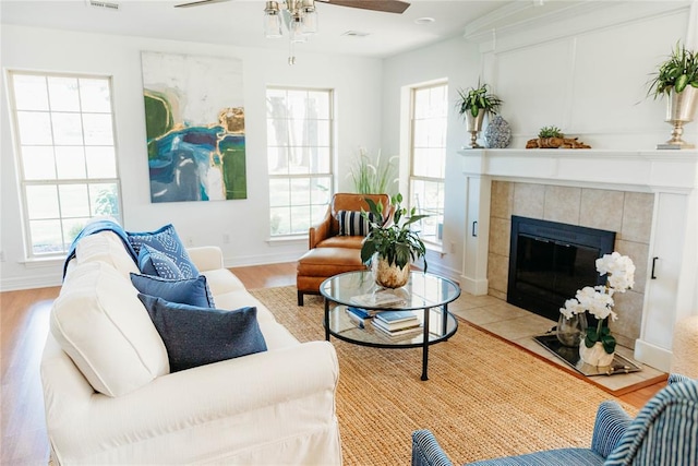 living room with ceiling fan, a fireplace, and light hardwood / wood-style flooring