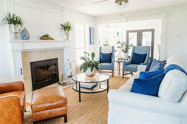 living room with a tile fireplace and ceiling fan