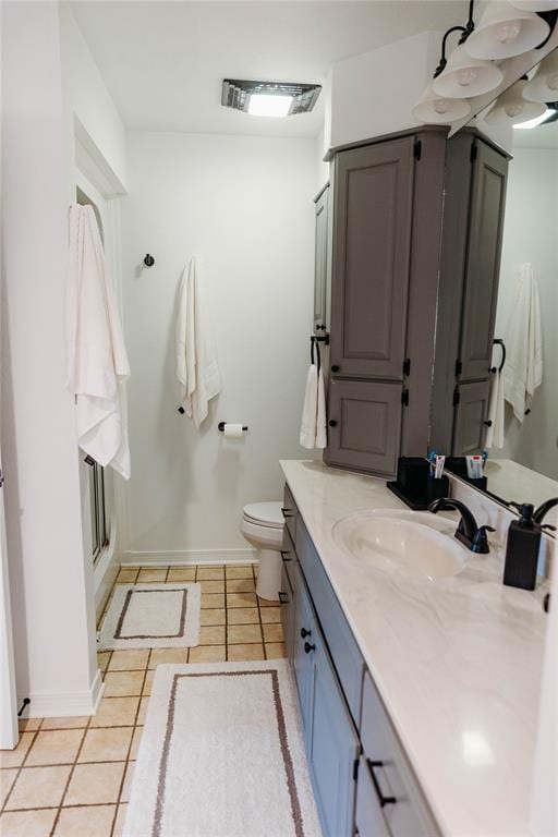 bathroom with toilet, vanity, tile patterned floors, and a shower with door