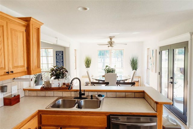 kitchen featuring ceiling fan, sink, french doors, stainless steel dishwasher, and decorative backsplash