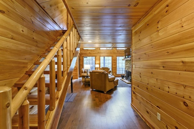 unfurnished living room with wood walls, a fireplace, wood ceiling, and dark hardwood / wood-style floors