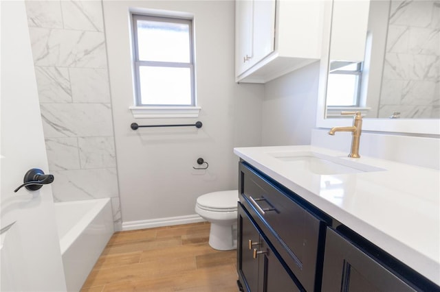 full bathroom with hardwood / wood-style flooring, vanity, tiled shower / bath combo, and toilet