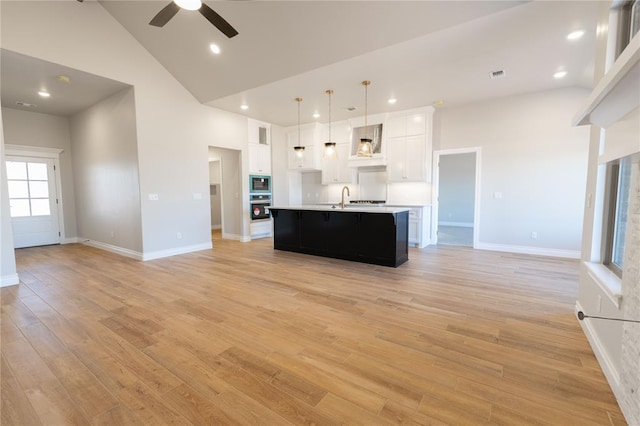 unfurnished living room featuring a healthy amount of sunlight, sink, high vaulted ceiling, and light hardwood / wood-style floors