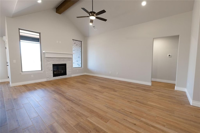 unfurnished living room featuring vaulted ceiling with beams, ceiling fan, a tiled fireplace, and light wood-type flooring