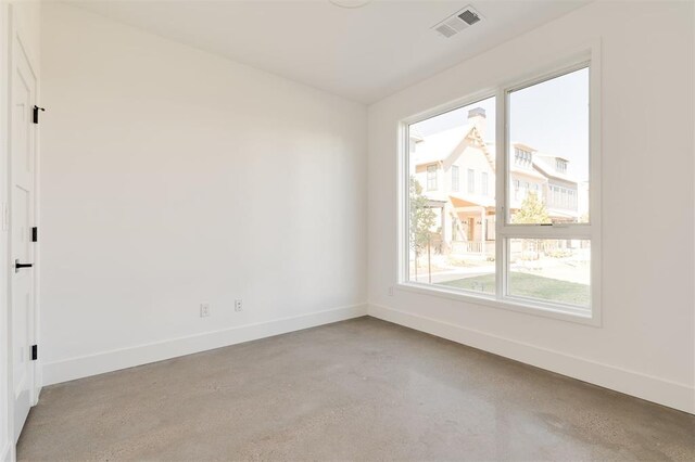 empty room with concrete flooring, baseboards, and visible vents