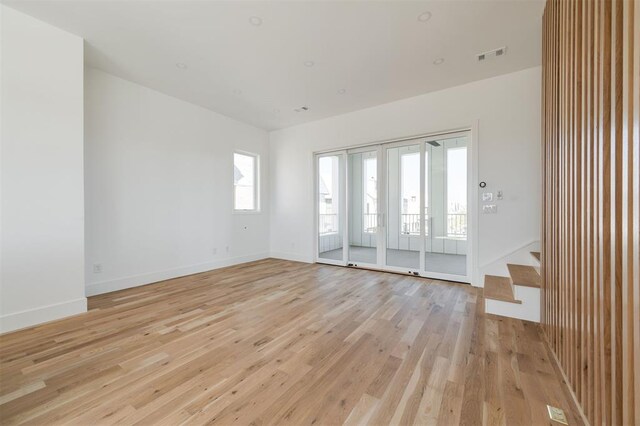 unfurnished room with light wood-style floors, baseboards, stairs, and visible vents