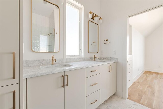 full bath featuring double vanity, a sink, marble finish floor, and a shower