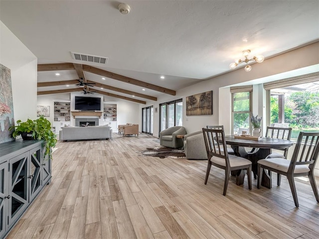 interior space featuring lofted ceiling with beams, a healthy amount of sunlight, light hardwood / wood-style floors, and ceiling fan with notable chandelier