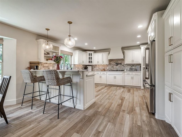 kitchen featuring custom exhaust hood, light hardwood / wood-style floors, white cabinetry, and stainless steel appliances