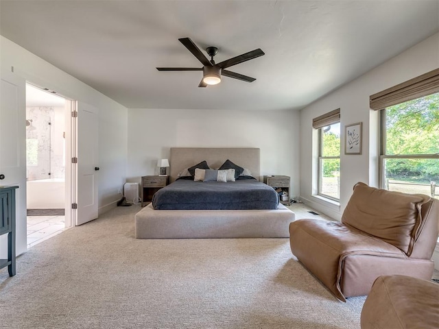 bedroom featuring light colored carpet, ensuite bath, and ceiling fan