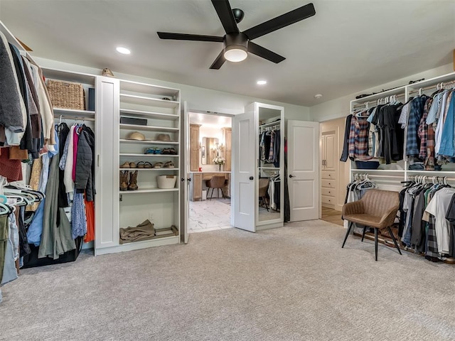 walk in closet with light colored carpet and ceiling fan