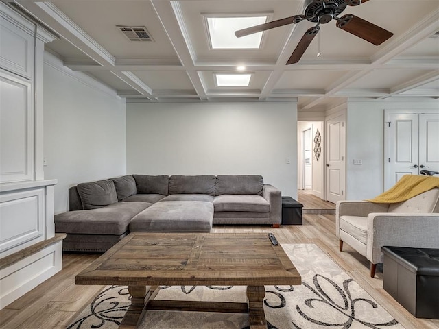 living room with ornamental molding, coffered ceiling, ceiling fan, light hardwood / wood-style flooring, and beamed ceiling