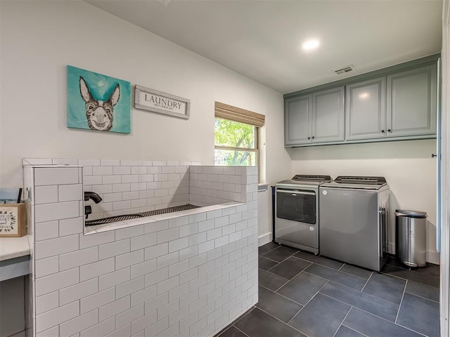 laundry room featuring washing machine and dryer, cabinets, and dark tile patterned flooring