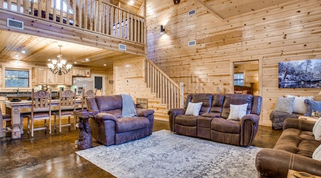 living room with a towering ceiling, wooden walls, sink, an inviting chandelier, and wooden ceiling