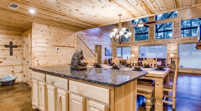 kitchen featuring dark stone countertops, wooden walls, wood ceiling, and decorative light fixtures