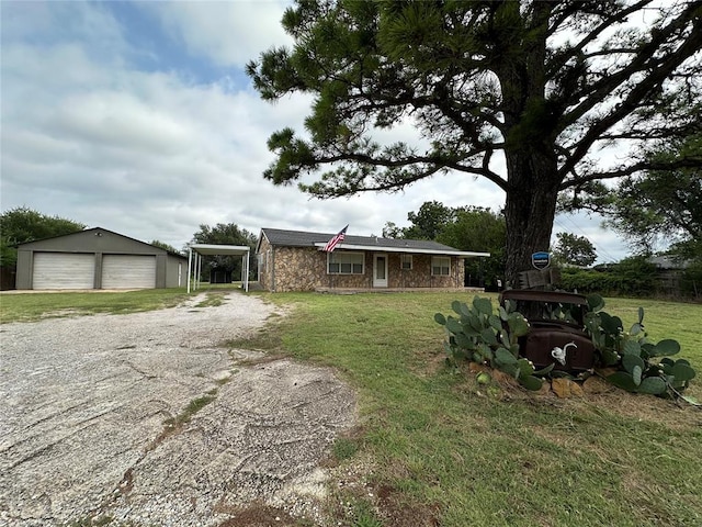 view of front of property featuring a carport, a garage, an outbuilding, and a front yard