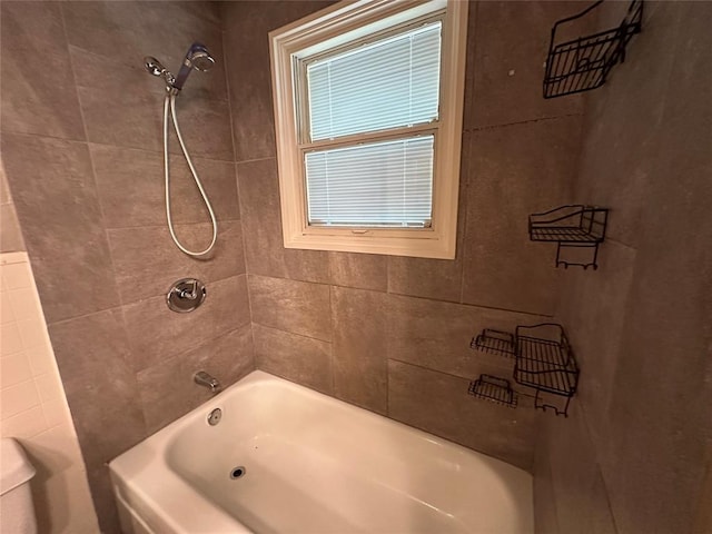 bathroom with toilet and tiled shower / bath