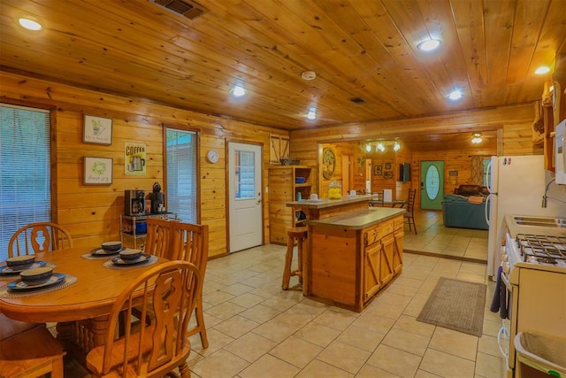 kitchen with wood walls, light tile patterned flooring, white appliances, and wood ceiling