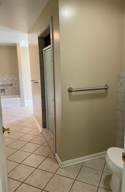 bathroom featuring tile patterned flooring, an enclosed shower, and toilet