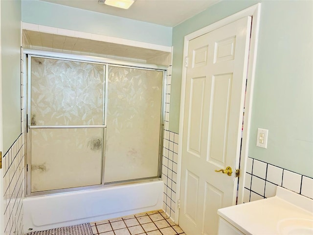 bathroom featuring bath / shower combo with glass door, tile patterned flooring, tile walls, and vanity