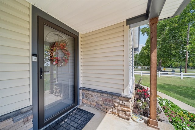 property entrance with a lawn and covered porch