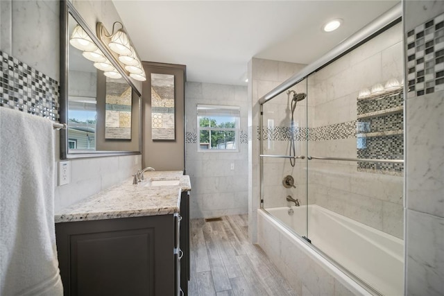 bathroom with hardwood / wood-style floors, vanity, and bath / shower combo with glass door