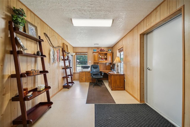 office with a textured ceiling and wooden walls