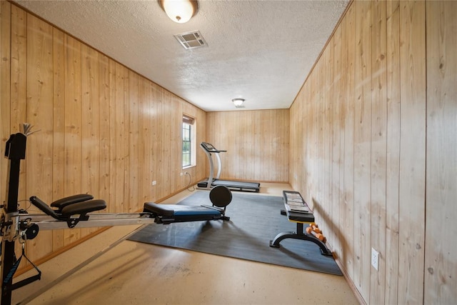 workout room with a textured ceiling and wood walls