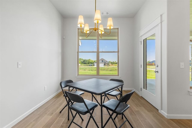 dining space with light hardwood / wood-style floors and a notable chandelier