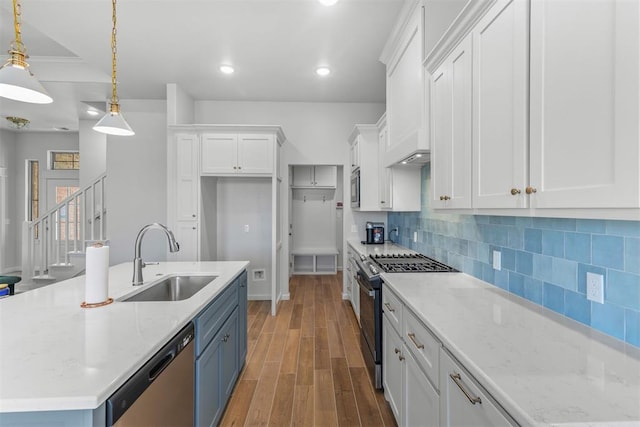 kitchen with pendant lighting, white cabinets, an island with sink, appliances with stainless steel finishes, and dark hardwood / wood-style flooring