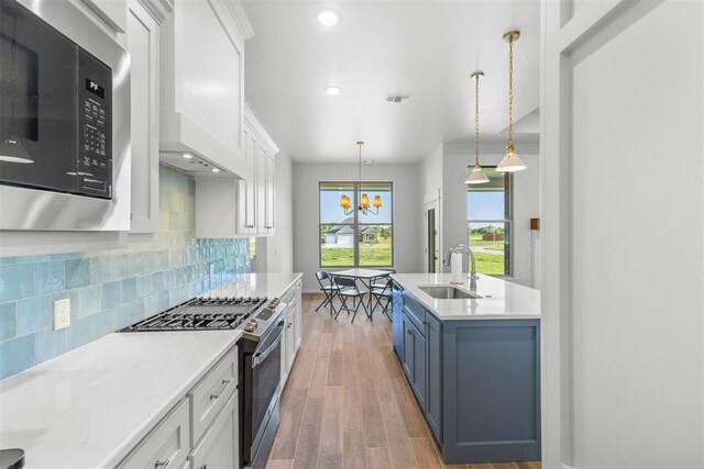 kitchen featuring sink, hardwood / wood-style floors, pendant lighting, white cabinets, and appliances with stainless steel finishes