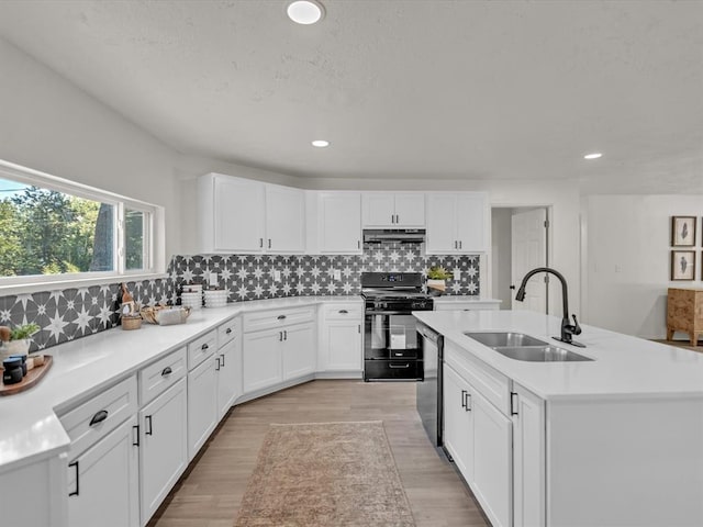 kitchen with black gas range, dishwasher, backsplash, sink, and an island with sink