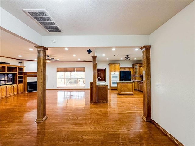 living room featuring light hardwood / wood-style floors, ornate columns, ceiling fan, and sink