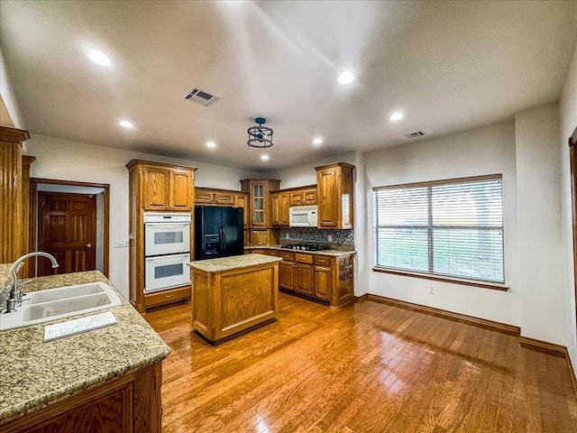 kitchen with a center island, white appliances, sink, light hardwood / wood-style flooring, and tasteful backsplash