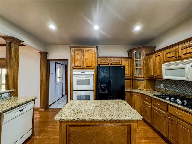 kitchen with black appliances, a center island, light stone countertops, and dark wood-type flooring