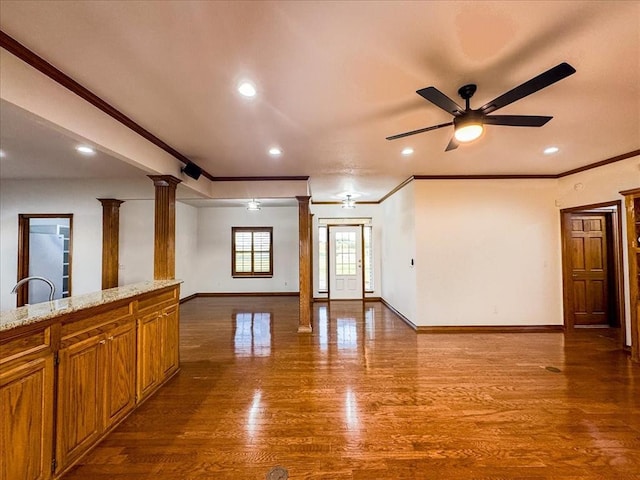 unfurnished room with decorative columns, ceiling fan, hardwood / wood-style floors, and crown molding