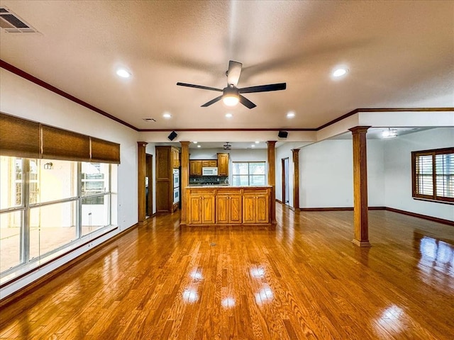 kitchen featuring ceiling fan, baseboard heating, decorative columns, crown molding, and wood-type flooring