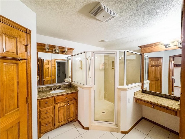 bathroom featuring tile patterned flooring, a shower with shower door, and a textured ceiling