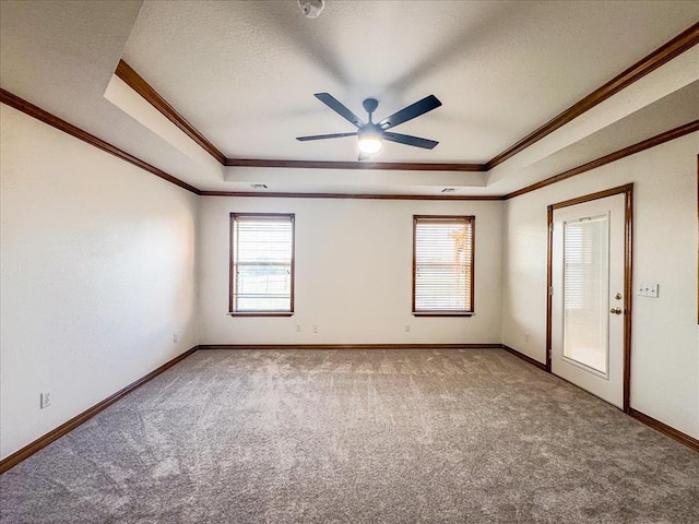 unfurnished room with a raised ceiling, plenty of natural light, and ornamental molding