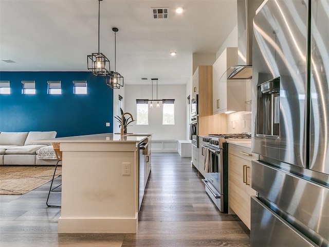 kitchen featuring wall chimney exhaust hood, a breakfast bar, stainless steel appliances, dark wood-type flooring, and a center island with sink